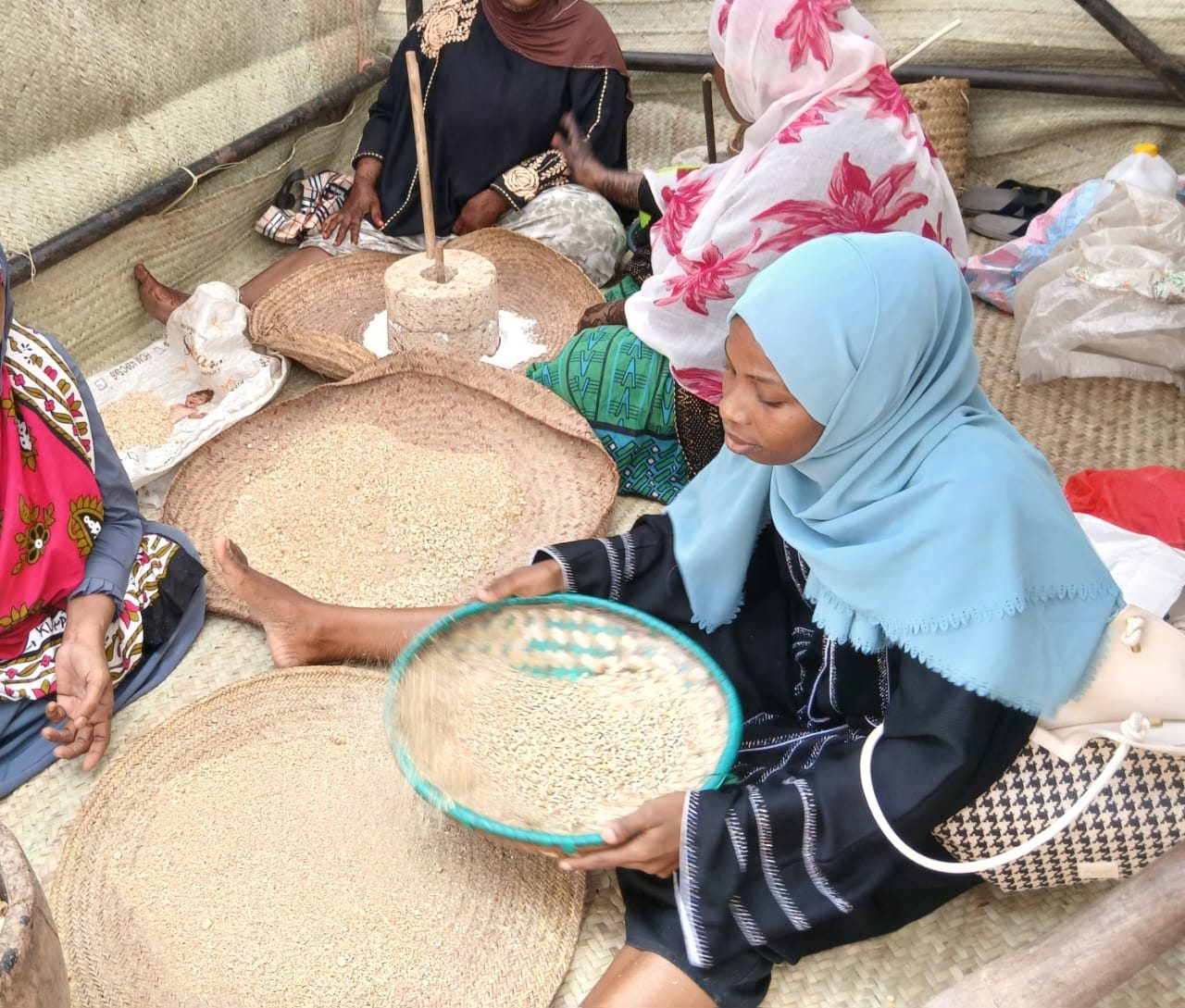 Women from the Pemba Community sifting grain together